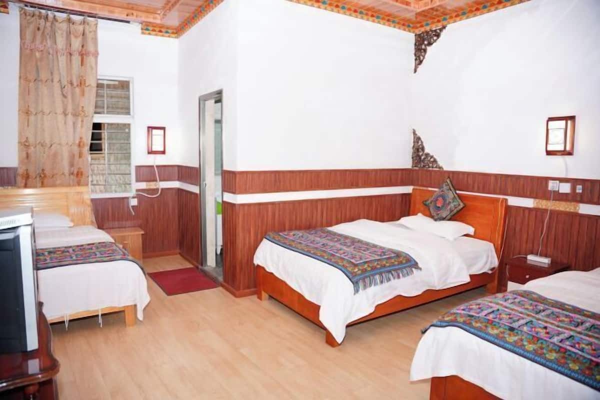 Une chambre d’hôtel avec deux lits, des panneaux de bois au mur, une télévision et une fenêtre avec des rideaux.