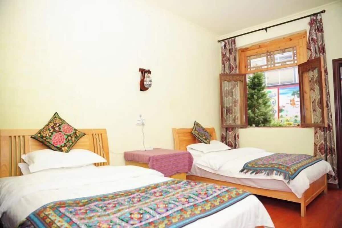 Une chambre avec deux lits, une fenêtre avec des rideaux et une horloge fixée au mur.