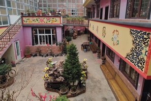 Une cour intérieure avec un espace de repos central, des plantes en pot et un escalier menant à un niveau supérieur.