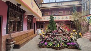 Ein Innenhof mit Blumenarrangement in der Mitte, einer Treppe und einem Gebäude mit traditioneller Architektur.