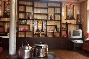 Una habitación con estantes de madera, un televisor y dos grandes contenedores metálicos.