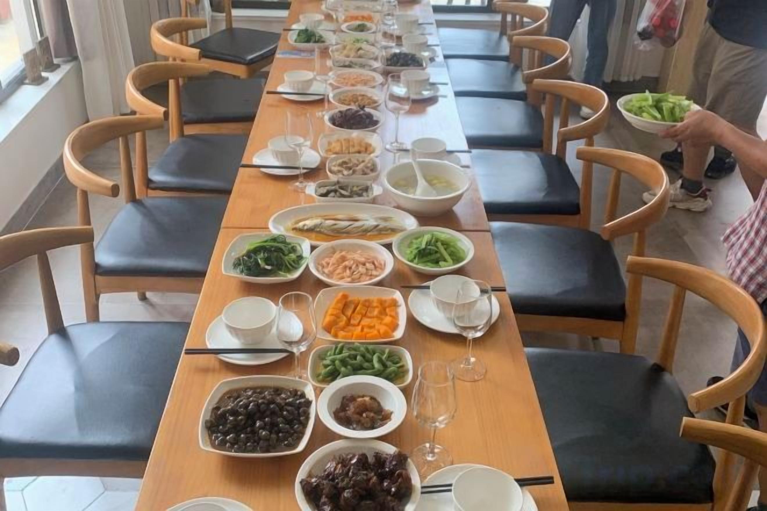 Una larga mesa de comedor con diversos platos y bebidas, rodeada de sillas.