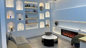 A modern living room with built-in shelving displaying decorative items, a round coffee table, a fireplace, and a sofa. - Lanhu Xiaozhu Hostel (Suzhou)