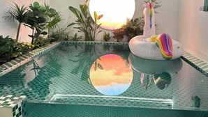 A pool with a glass bottom, surrounded by tropical plants and a large circular mirror reflecting the sky. - Lanhu Xiaozhu Hostel (Suzhou)