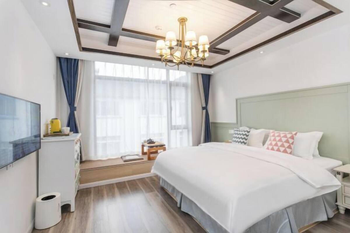 Habitació d'hotel moderna amb un llit gran, una televisió, una taula de treball i un penjador de cristall.