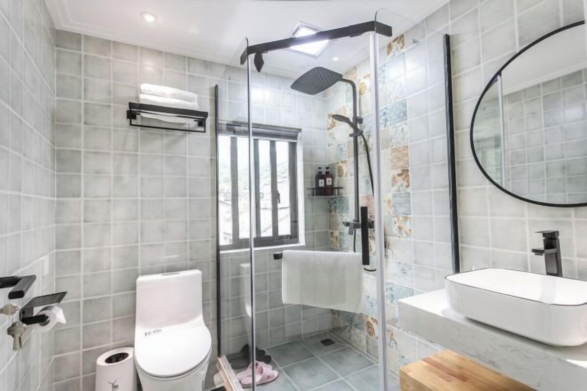 A modern bathroom with a glass-enclosed shower, a white sink, and a mirror.