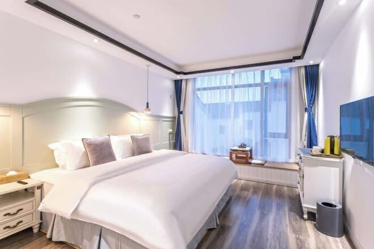 Habitació d'hotel moderna amb un llit gran, taules de nit, un escriptori i vista a la ciutat.