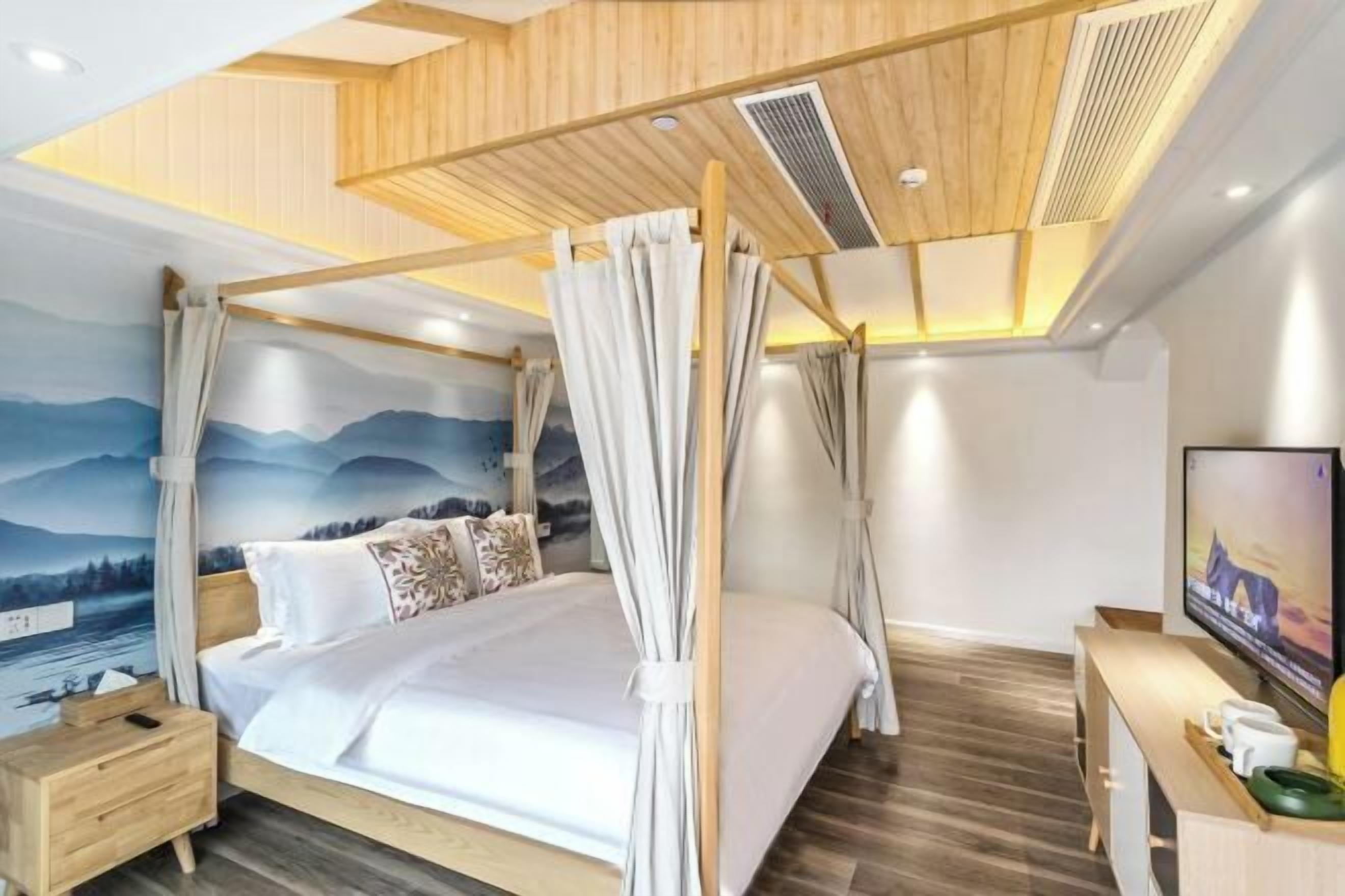 Quarto moderno com cama de dossel, cabeceira de madeira, mesa de cabeceira, televisão e um mural com paisagem de montanhas.