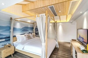 Un dormitorio moderno con cama a dosel, cabecera de madera, mesita de noche, televisor y un mural de montañas.