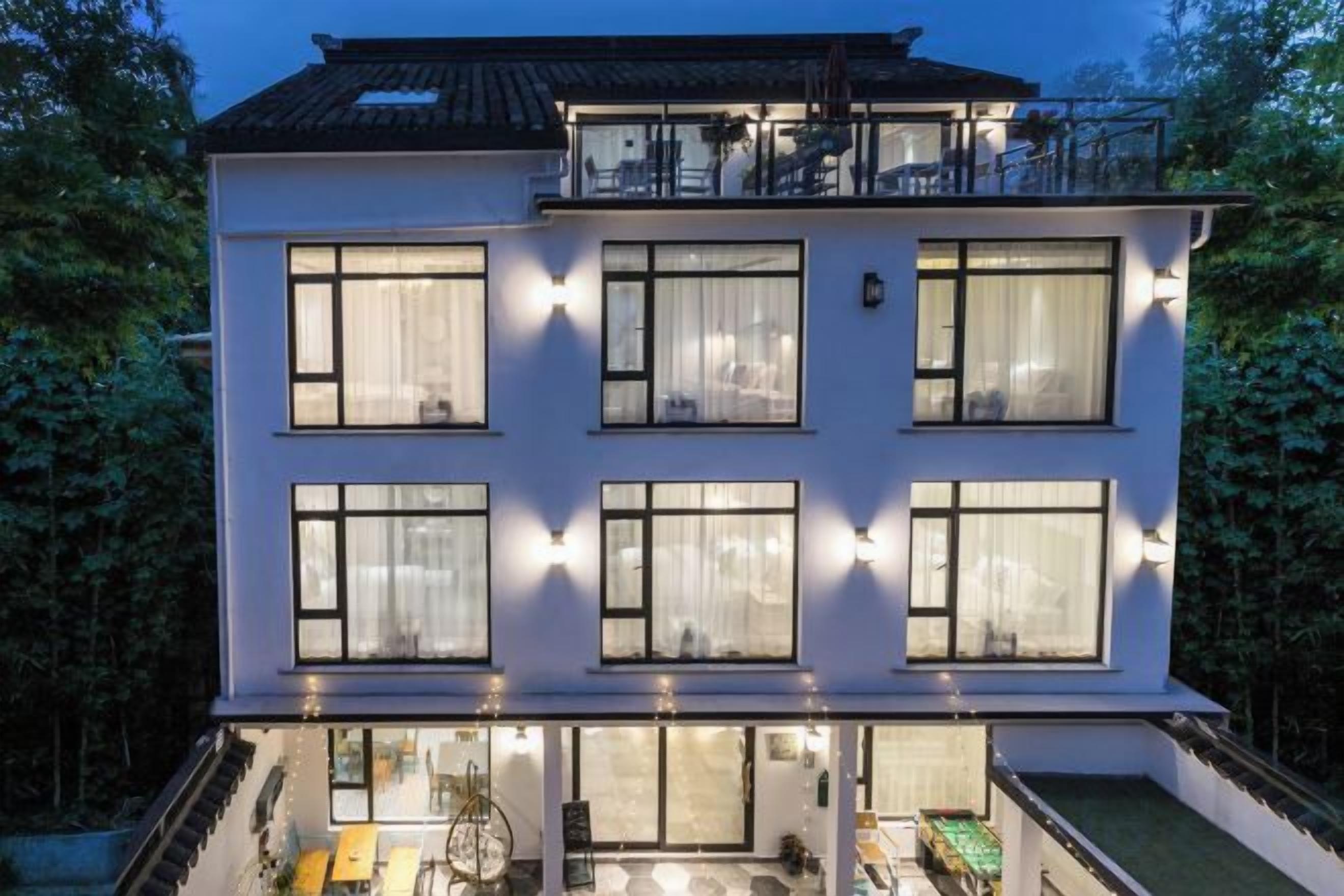 Un edificio de varios pisos con ventanas amplias, un balcón y un interior bien iluminado.