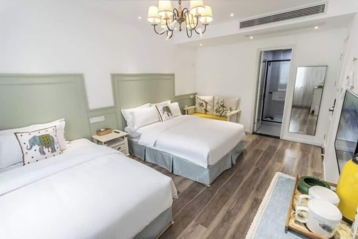 Una habitació d'hotel amb dos llits, una làmpada de cristall, un mirall i una taula petita amb una safata d'objectes.