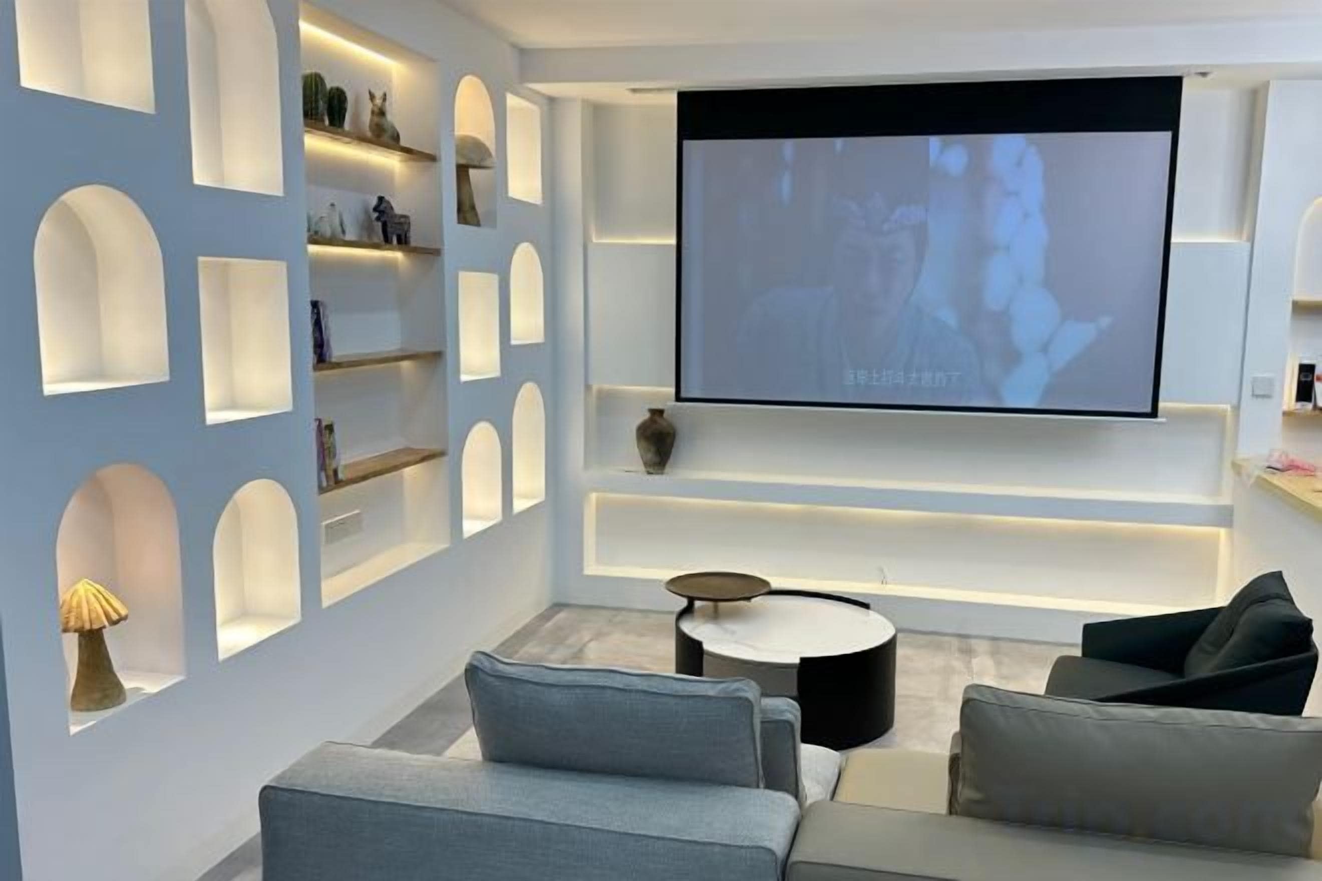 Un salon moderne doté d’un téléviseur à écran plat, d’étagères intégrées et d’une table basse ronde.