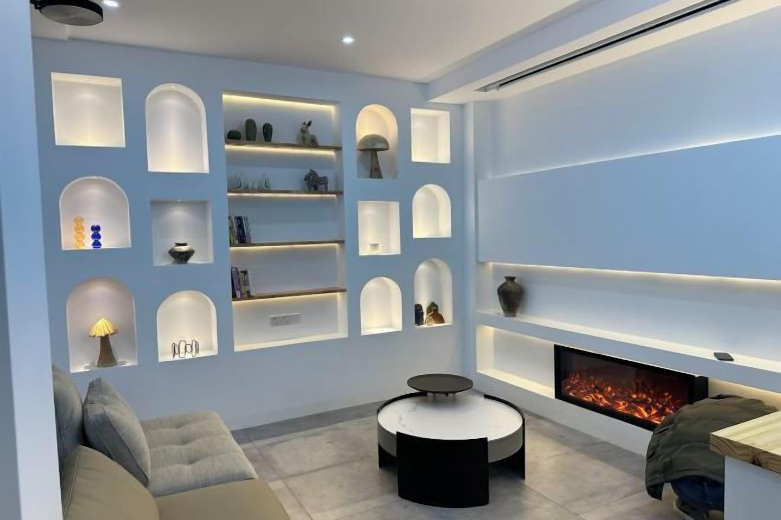 A modern living room with built-in shelving, a fireplace, and a round coffee table.