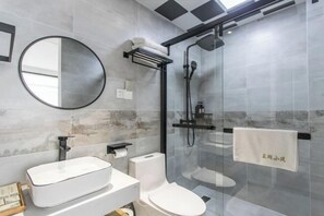 A modern bathroom with a glass-enclosed shower, a round mirror, a white sink, and a toilet. - Lanhu Xiaozhu Hostel (Suzhou)