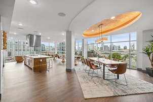 A modern hotel lobby with a large dining area, a kitchen, and large windows offering city views.