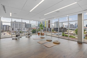 A spacious gym with large windows, exercise equipment, and a city view.