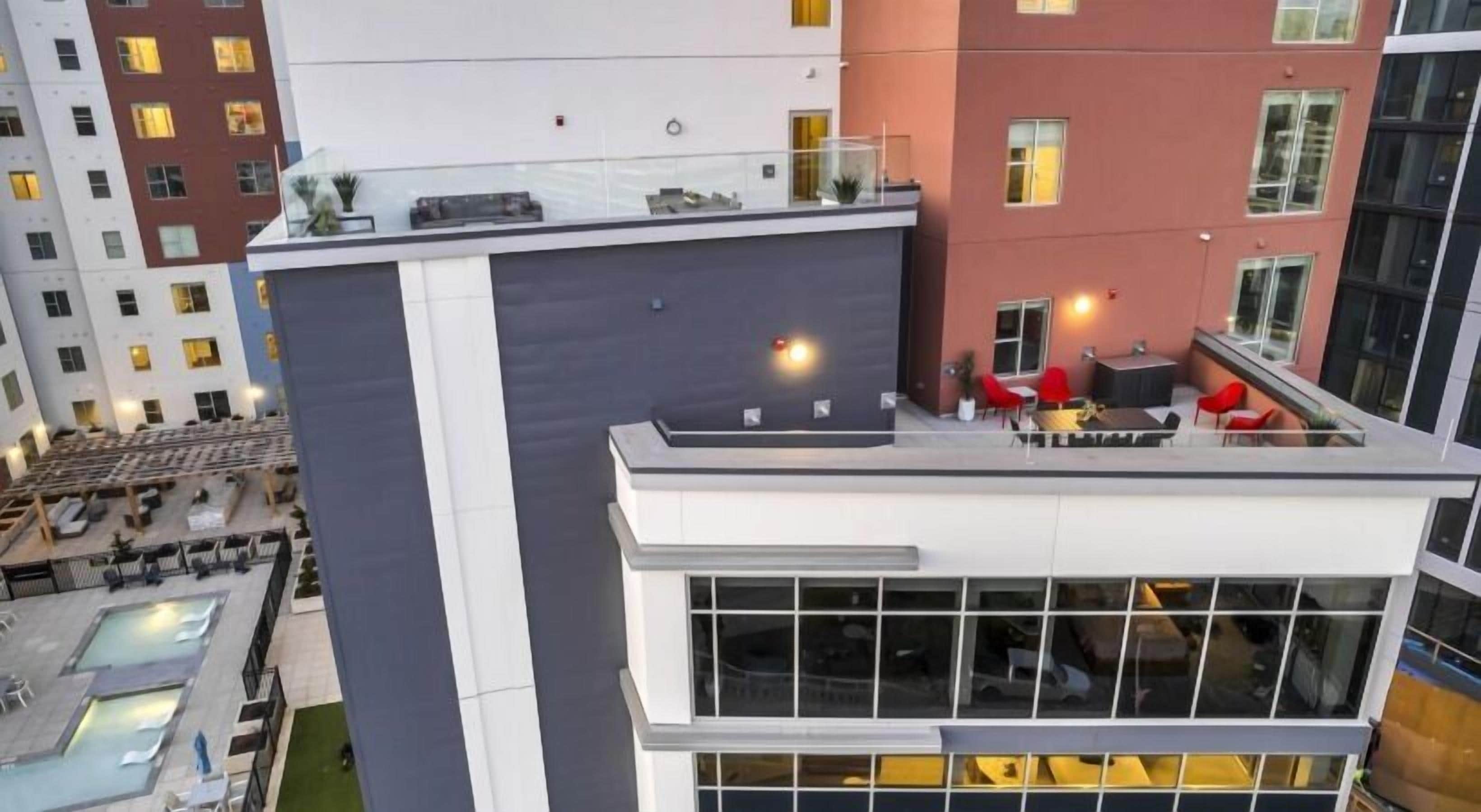 Ein modernes Gebäude mit Dachterrasse, Außenbereich zum Sitzen und einem Pool.