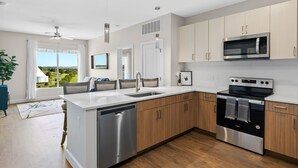 A modern kitchen with a dishwasher, oven, microwave, and wooden cabinets. - Beverly Hills Penthouse Suite (Nashville)