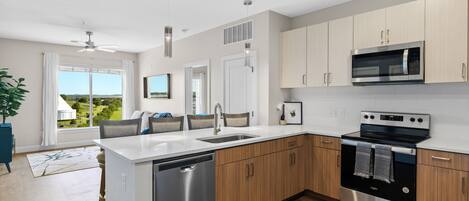 A modern kitchen with a dishwasher, oven, microwave, and wooden cabinets.