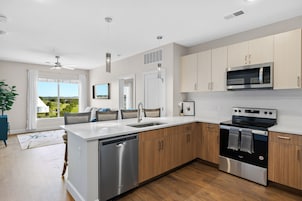 A modern kitchen with a dishwasher, oven, microwave, and wooden cabinets.