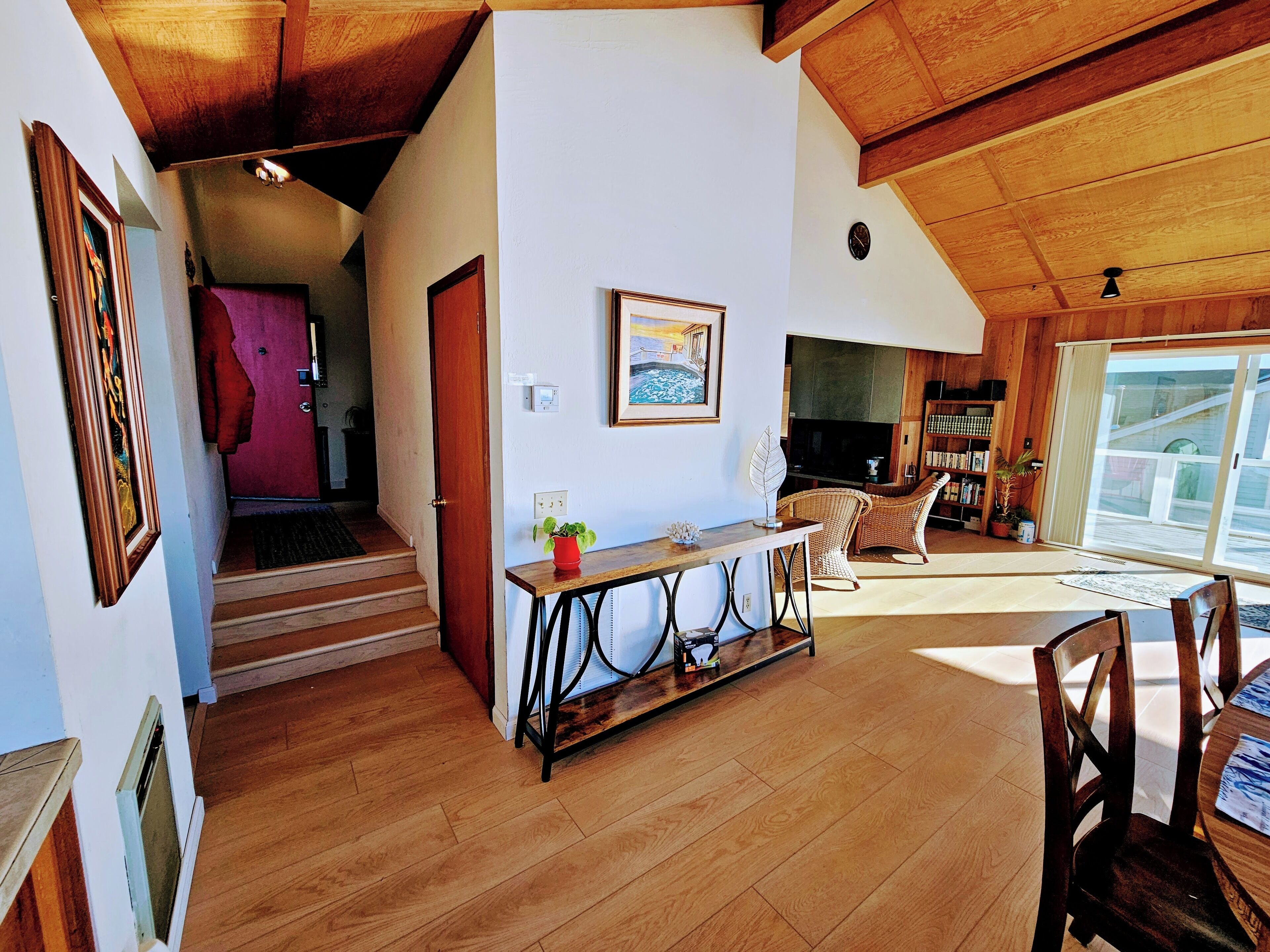Un vaste espace de vie doté d’un plafond en bois, d’une cheminée, d’une table à manger avec des chaises et d’une grande fenêtre offrant une vue imprenable.