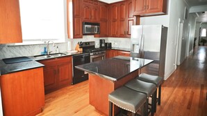 A kitchen with wooden cabinets, a black countertop, stainless steel appliances, and a marble backsplash.