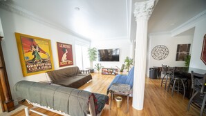 A living room with a sofa, a coffee table, a TV, and a dining area with chairs.