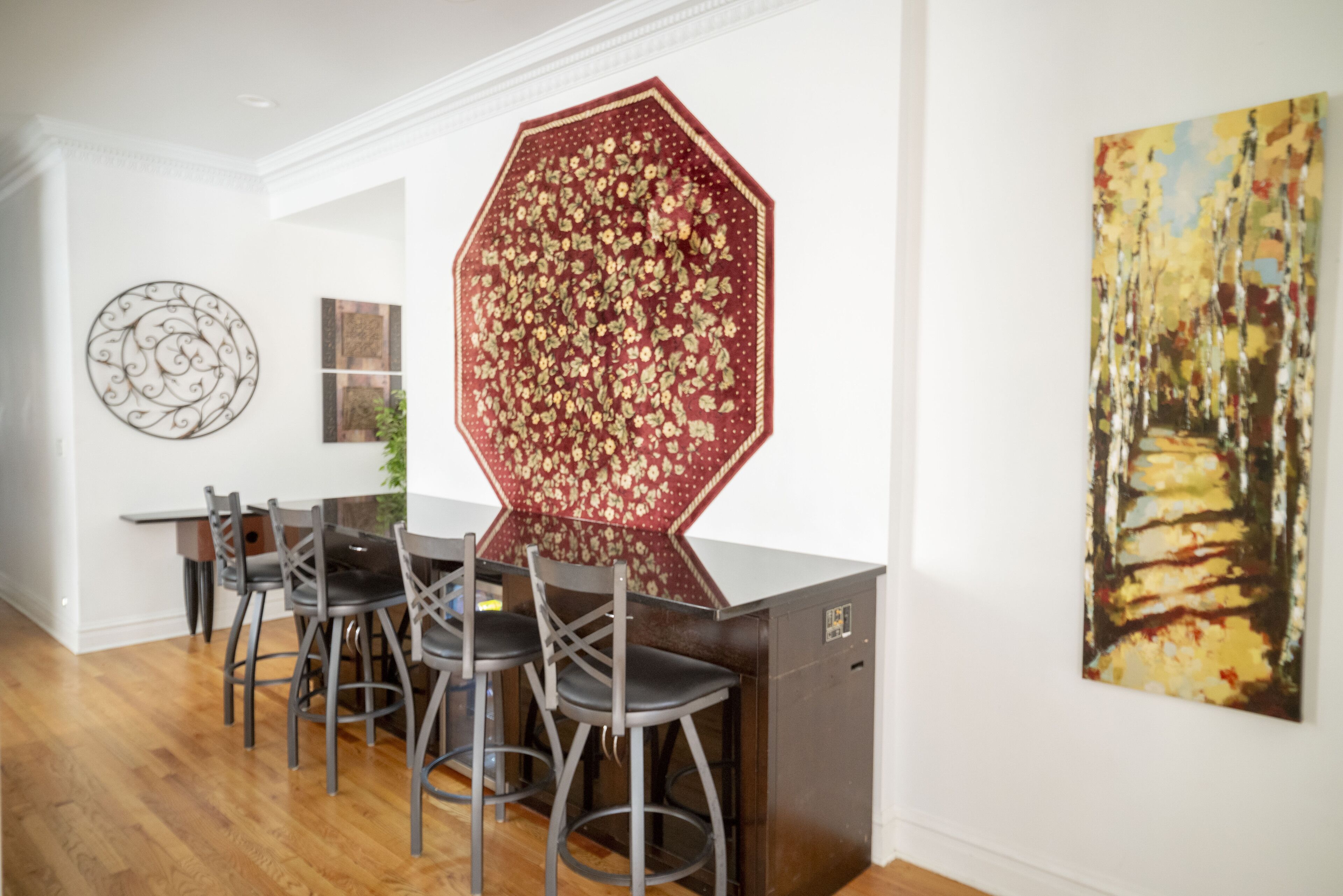 A dining area with a wooden table, four chairs, and a decorative wall piece.