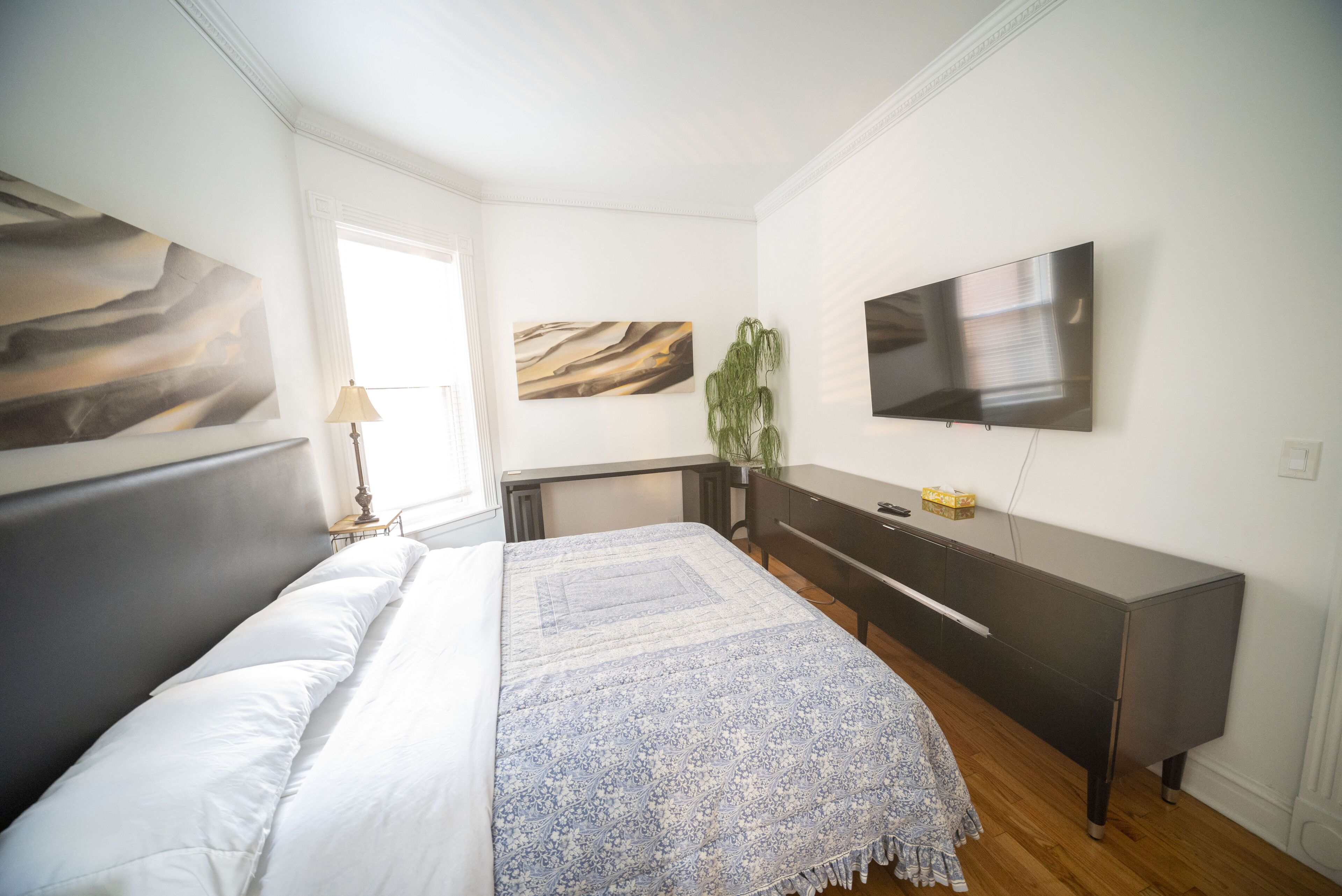 Ein modernes Schlafzimmer mit einem großen Bett, einem Flachbildfernseher und Kunstwerken an den Wänden.