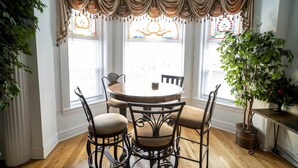 A dining room with a round table, four chairs, and a potted plant.