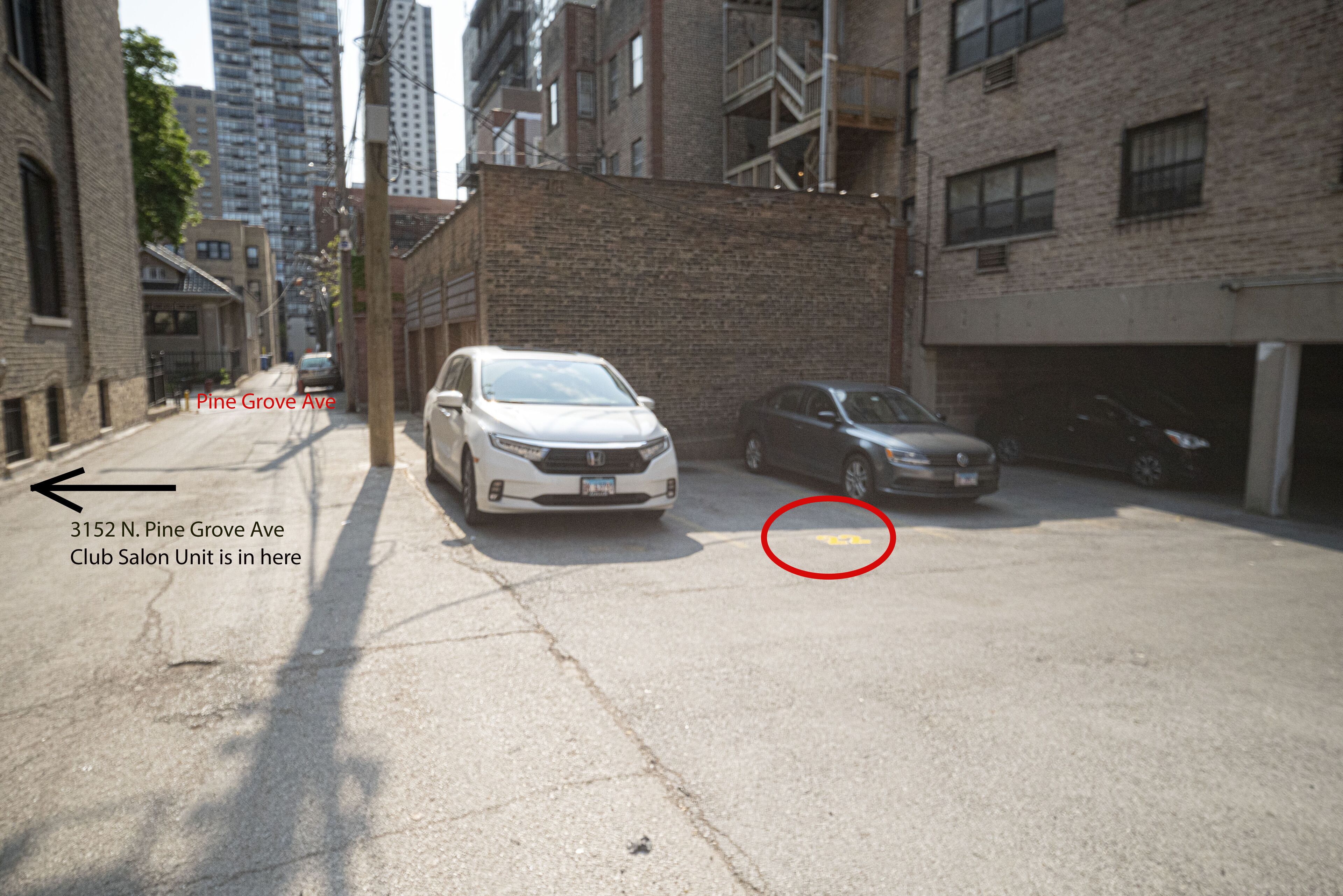 Una calle urbana estrecha con coches aparcados y edificios altos.