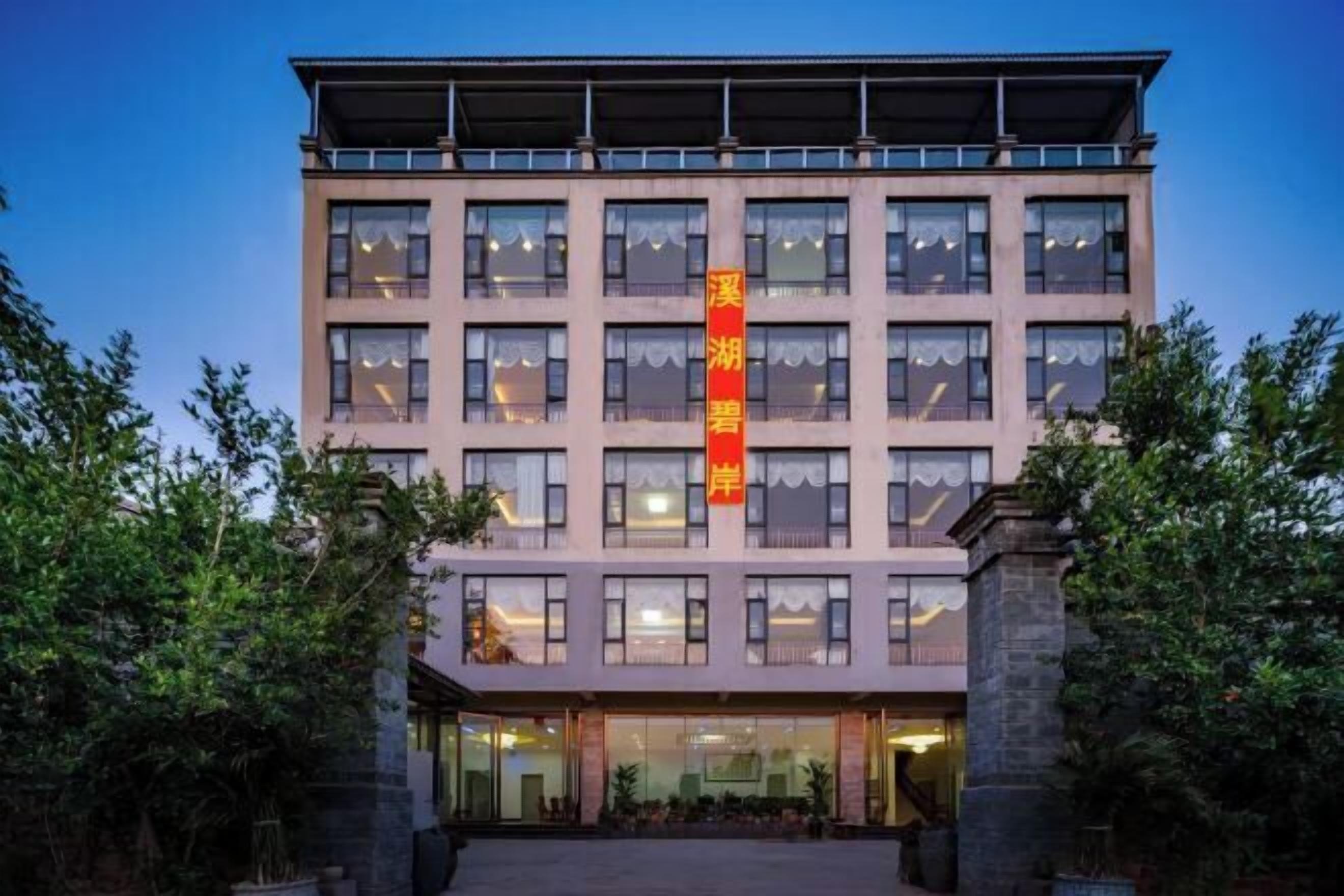 A multi-story building with a prominent vertical sign, large windows, and a stone facade.
