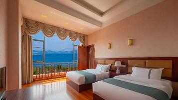 Ein Hotelzimmer mit zwei Betten, Meerblick und einem Balkon.