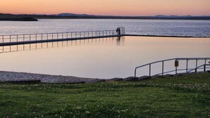 Una orilla tranquila con un puente peatonal y zonas verdes.