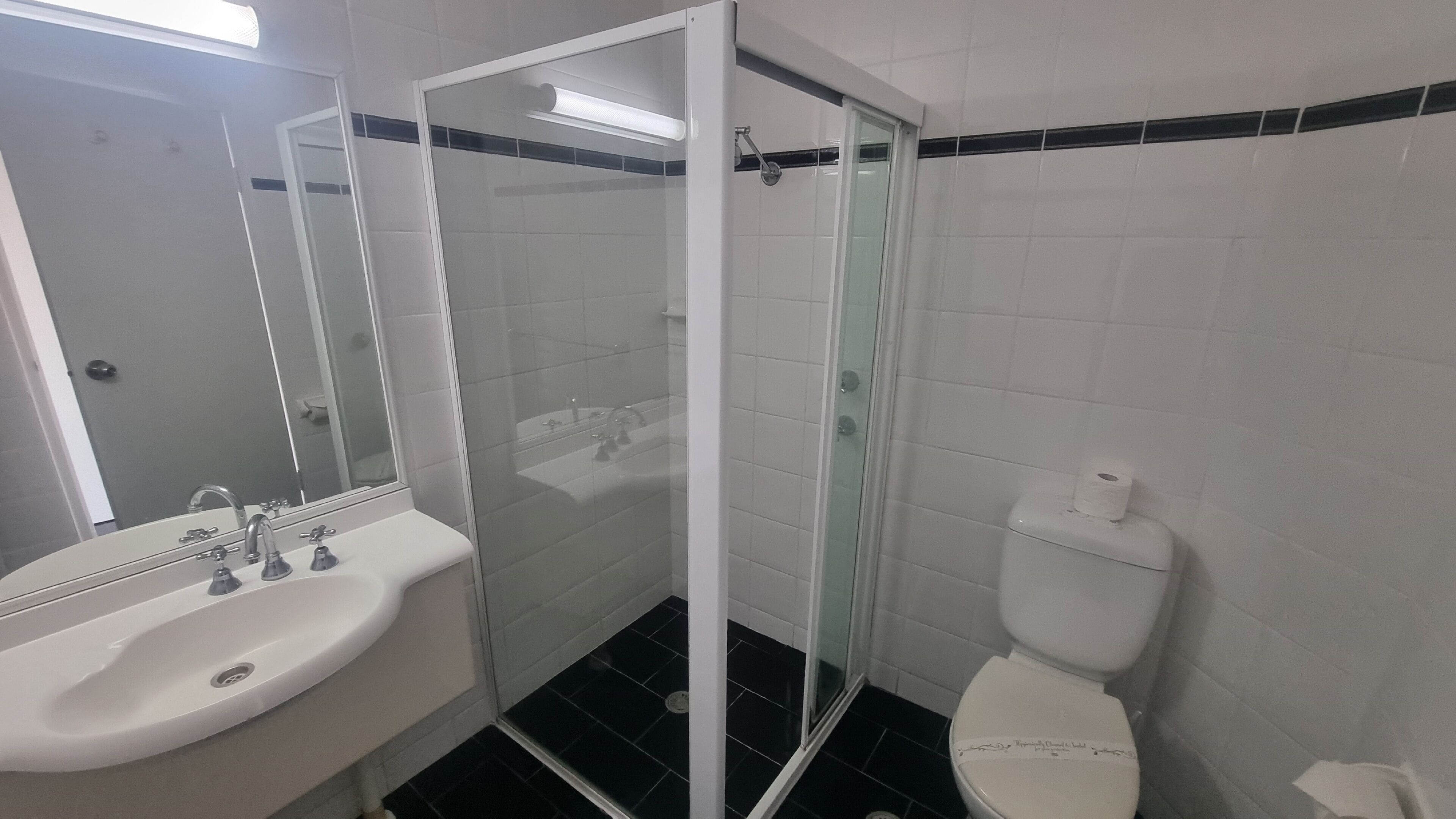A bathroom with a white sink, a glass-enclosed shower, and a toilet.