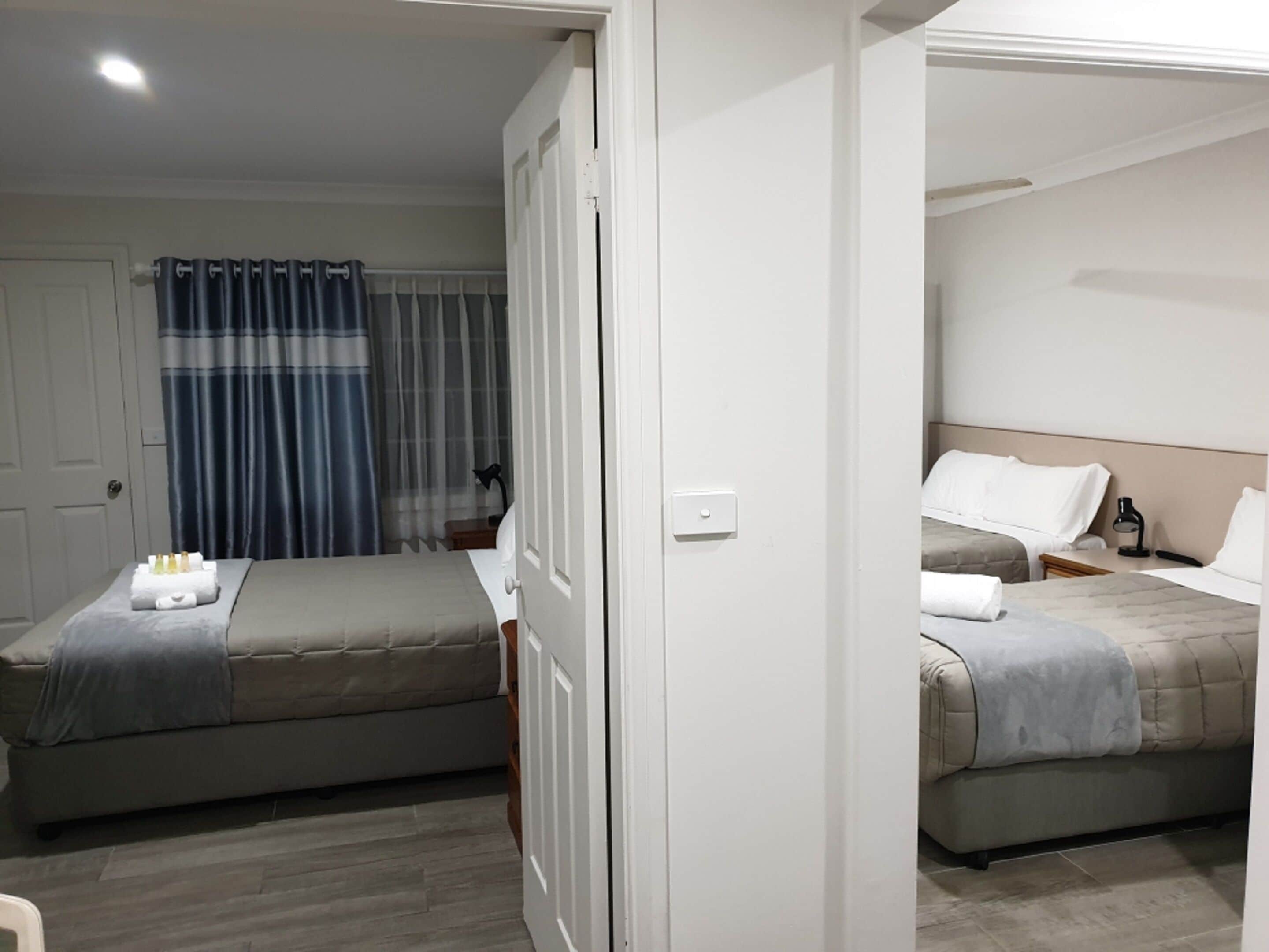 Habitación de hotel con dos camas, baño y vista a la calle.