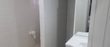 A bathroom with white tiled walls and a white toilet.