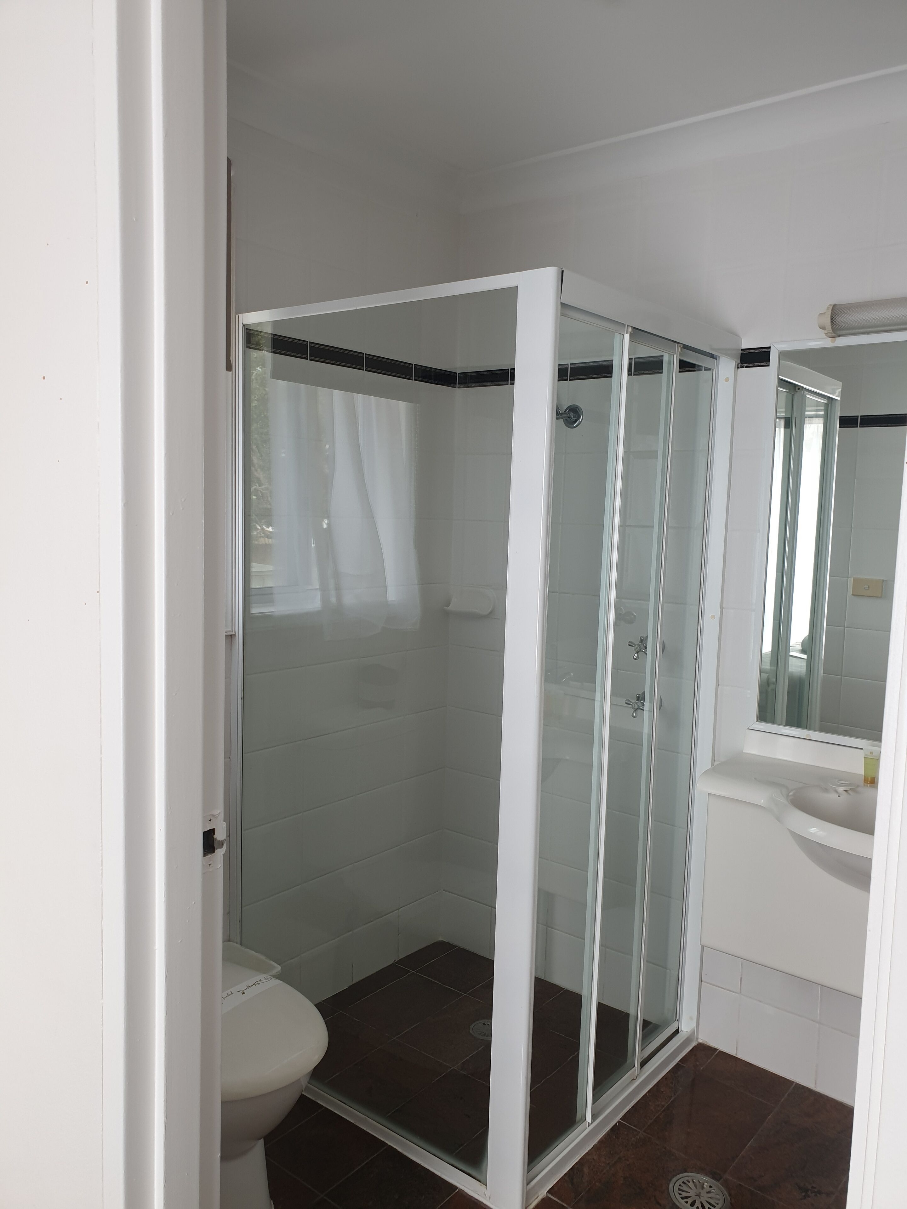 A bathroom with a glass-enclosed shower, a toilet, and a sink.