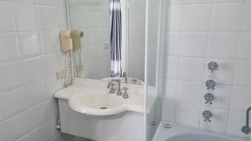 A bathroom with a white sink, a mirror, a shower with a glass door, and a bathtub.