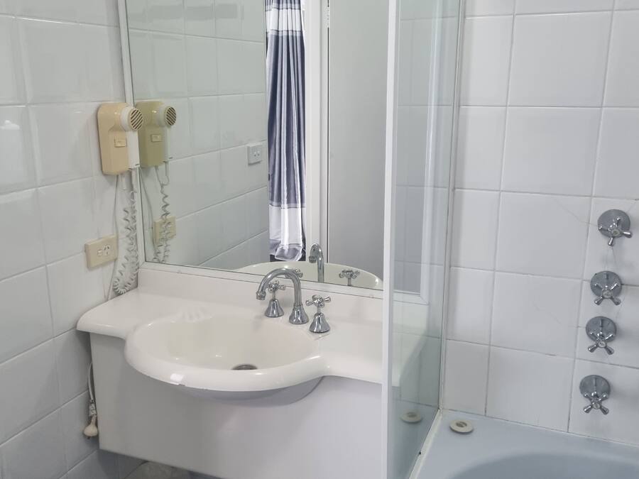 A bathroom with a white sink, a mirror, a shower with a glass door, and a bathtub.