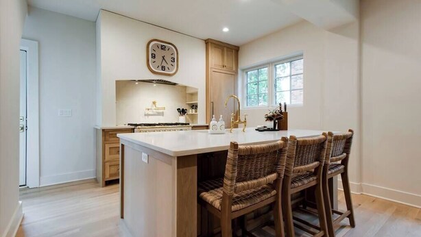 Una cocina con una isla central, armarios de madera, un reloj y una ventana.