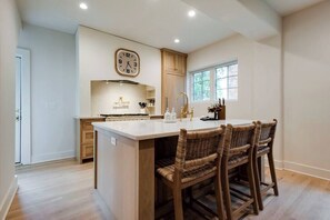 A kitchen with a central island, wooden cabinets, a clock, and a window. - Lux West Nash Tudor, 4mi to DT, Sleeps 9 (Nashville)