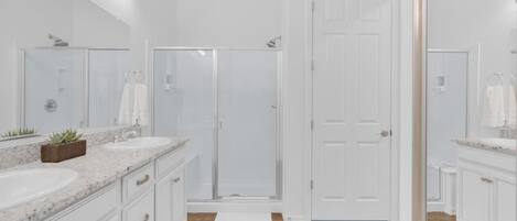 Un baño moderno con dos lavamanos, una ducha y una puerta.