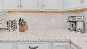A kitchen with white cabinets, a marble countertop, a knife block, and a coffee maker. - Design Dream / View / 4 BR 3 BA / Upscale / Garage (Sahuarita)