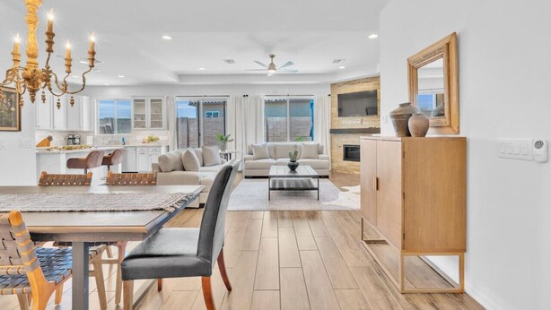 A spacious living area with a dining table, chairs, a sofa, and a coffee table. There is a chandelier, a fireplace, and a large mirror on the wall. - Design Dream / View / 4 BR 3 BA / Upscale / Garage (Sahuarita)