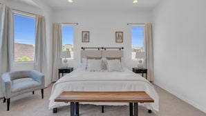 A bedroom with a large bed, two bedside tables, a chair, and a bench. - Design Dream / View / 4 BR 3 BA / Upscale / Garage (Sahuarita)