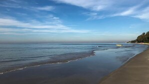 Een strand met een heldere lucht en rustig water.