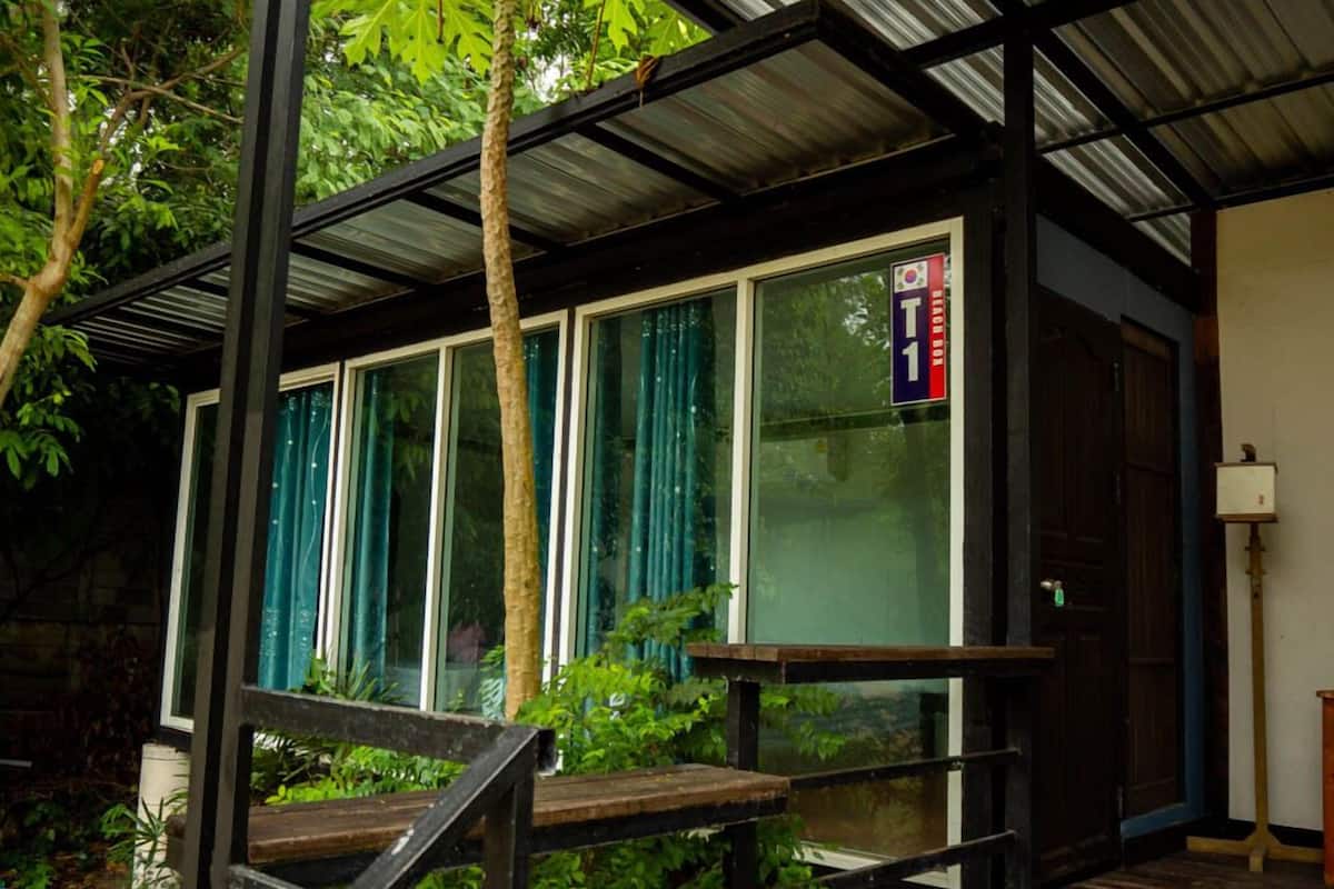 A modern building with large windows, a metal roof, and a wooden deck.