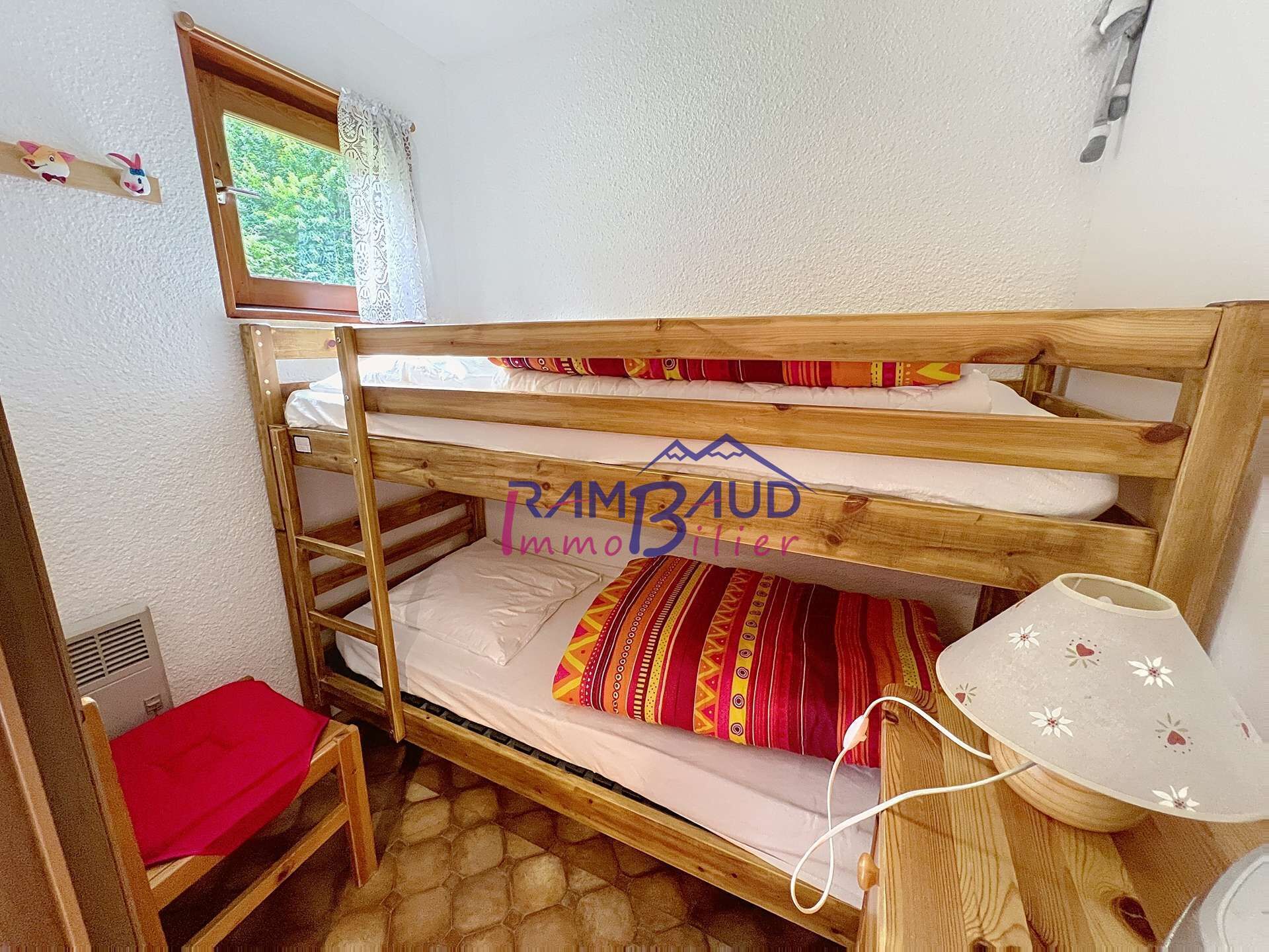 Habitación con literas, una mesita y una silla roja.