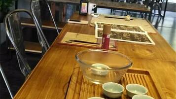 A wooden table with a glass bowl and several small bowls, likely for tea or snacks, in a dining area with chairs and a bottle.